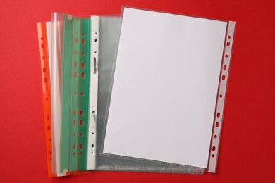 Photo of File folders with punched pockets on red background, flat lay