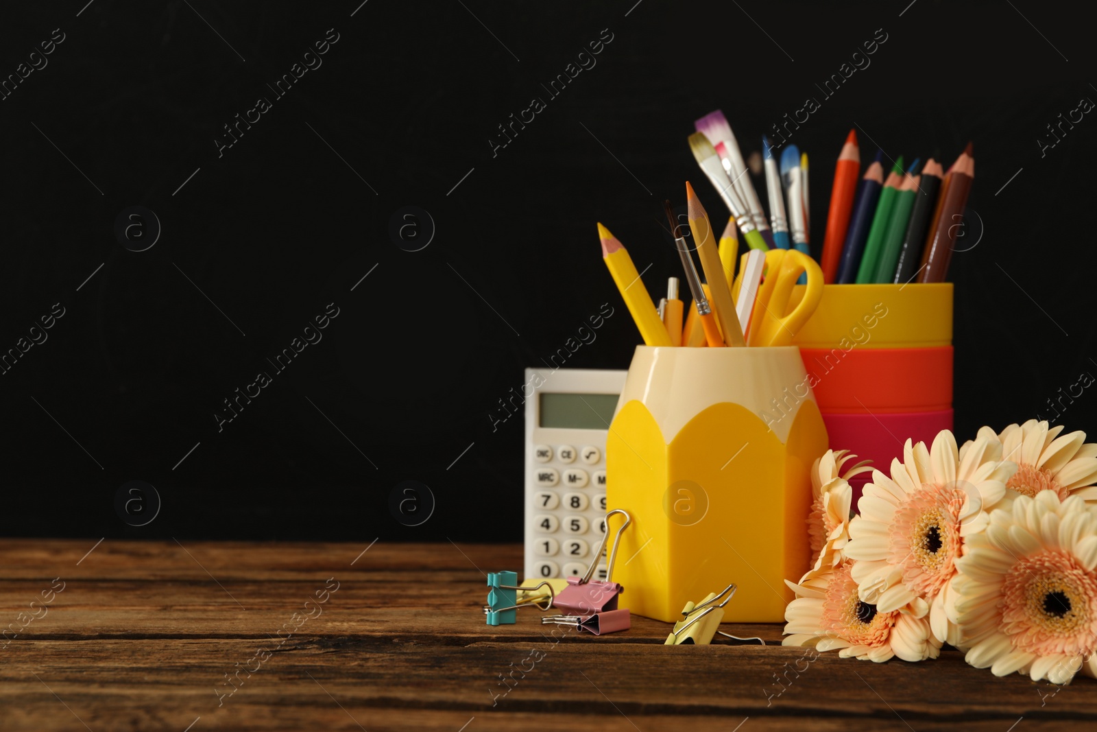 Photo of Set of stationery and flowers on wooden table near chalkboard, space for text. Teacher's Day