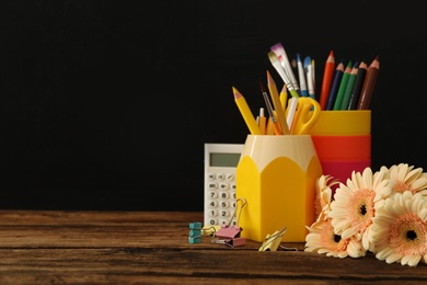 Photo of Set of stationery and flowers on wooden table near chalkboard, space for text. Teacher's Day