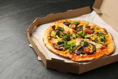 Photo of Delicious vegetarian pizza with mushrooms and vegetables in box on black table