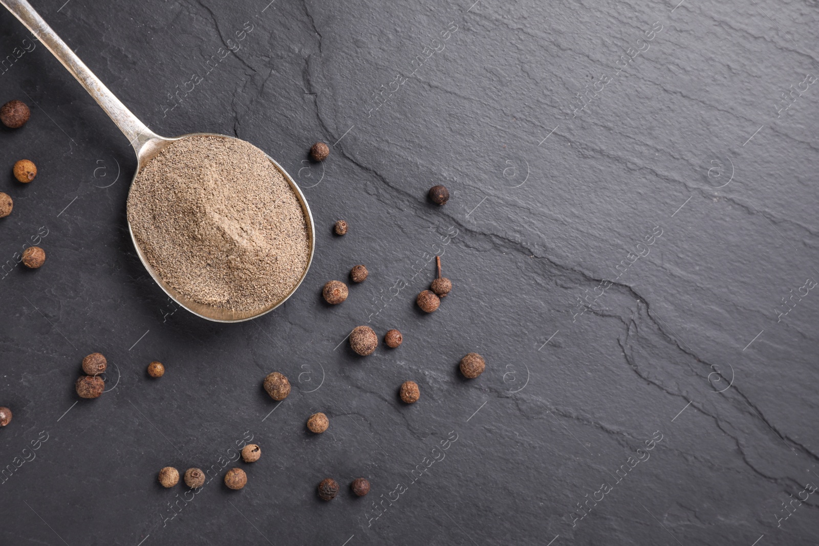 Photo of Ground black pepper and corns on black table, flat lay. Space for text