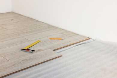 Photo of Ruler, pencil and parquet planks on floor in room prepared for renovation