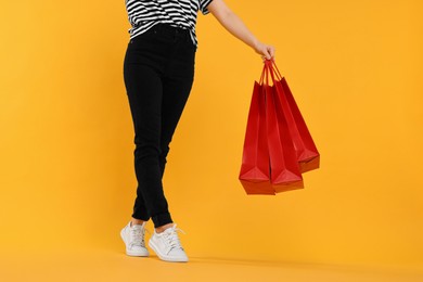 Woman with shopping bags on yellow background, closeup