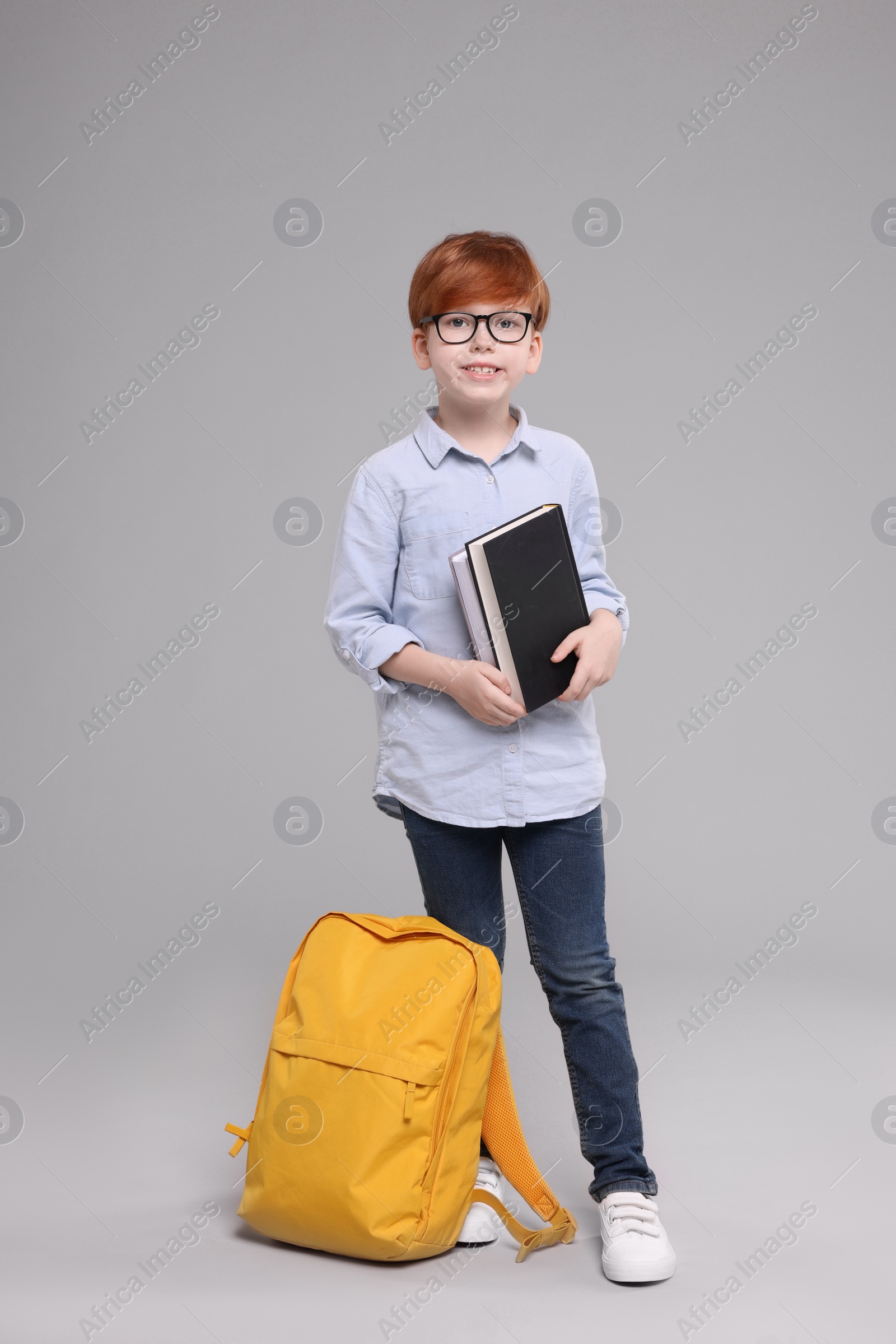 Photo of Happy schoolboy with books on grey background