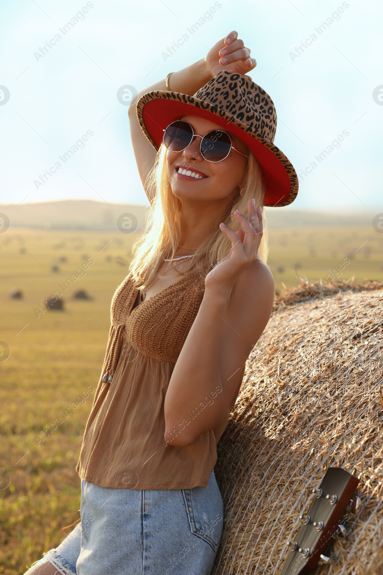 Photo of Happy hippie woman near hay bale in field