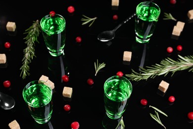 Photo of Absinthe in shot glasses, cranberries, rosemary and brown sugar on mirror table. Alcoholic drink