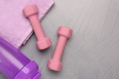 Photo of Dumbbells, water shaker and towel on light grey table, flat lay. Space for text