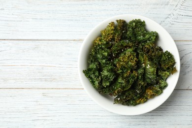 Photo of Tasty baked kale chips on white wooden table, top view. Space for text