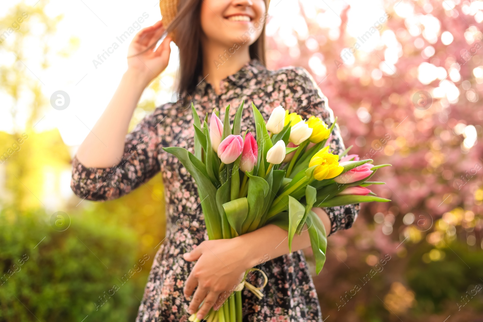 Photo of Young woman with bouquet of tulips in park on sunny day, closeup