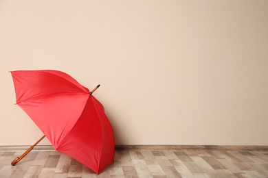 Photo of Colorful umbrella on floor against beige wall. Space for text