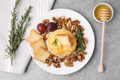 Tasty baked camembert and different products on gray textured table, flat lay