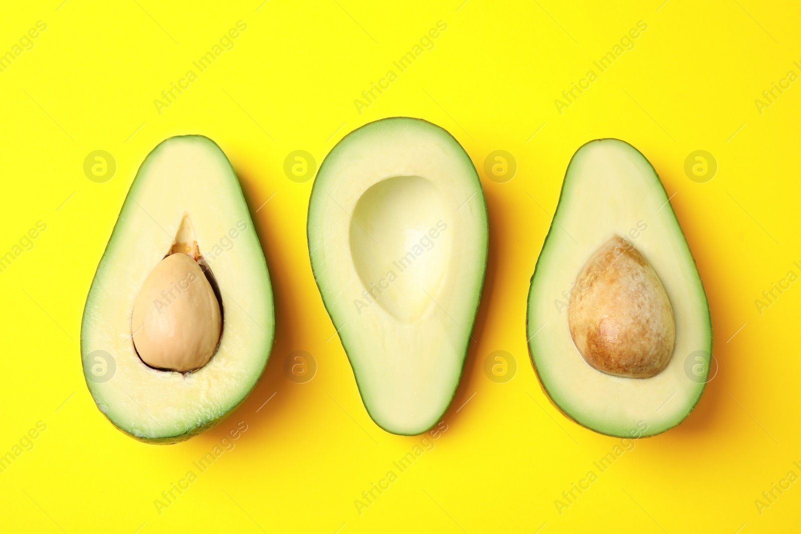 Photo of Cut fresh ripe avocados on yellow background, flat lay