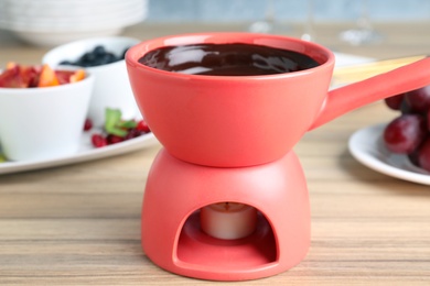 Photo of Ceramic pot with chocolate fondue on table