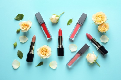 Flat lay composition with lipsticks and roses on color background