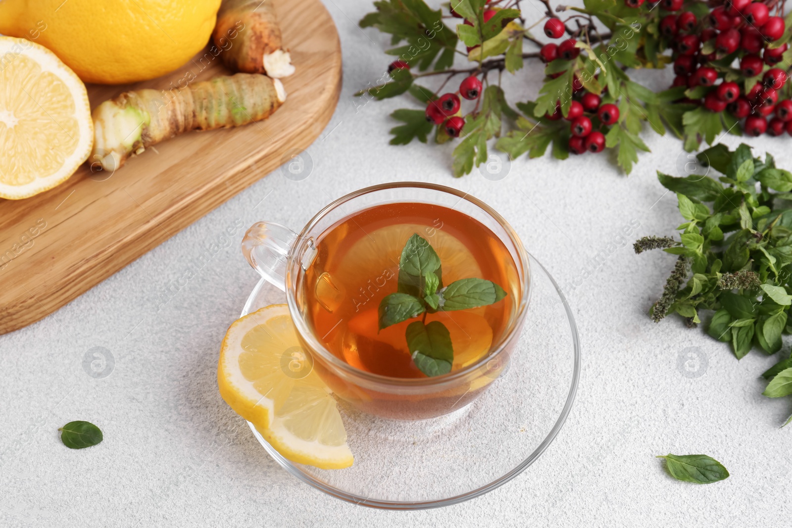 Photo of Glass cup of delicious immunity boosting tea with ingredients on light grey table, above view