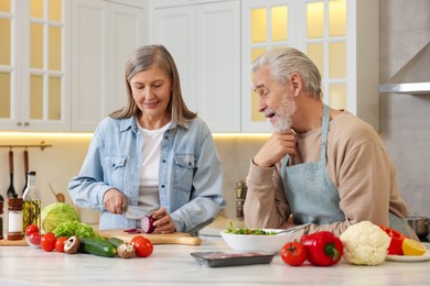 Photo of Happy senior couple cooking together in kitchen