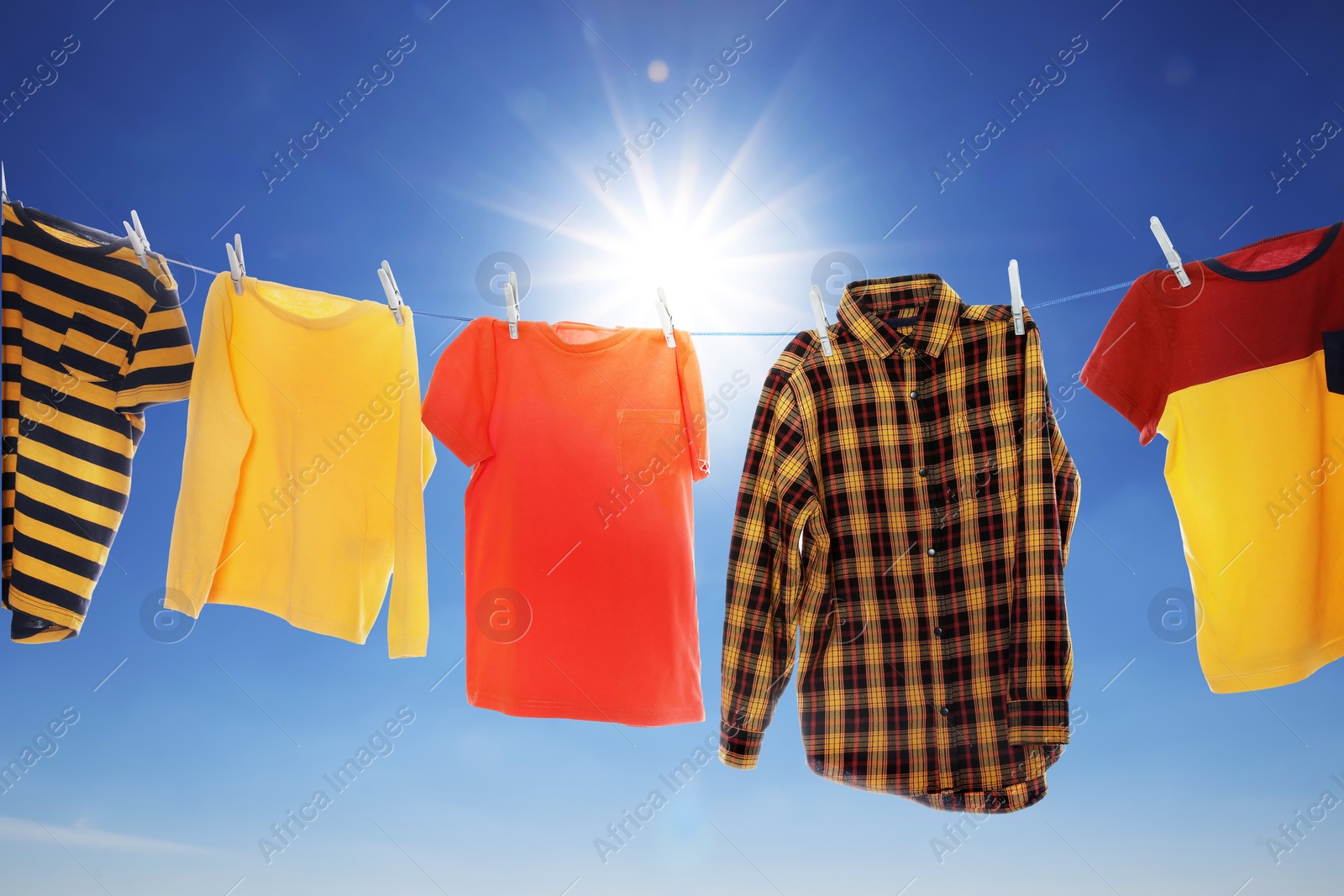 Image of Different clothes drying on washing line against blue sky