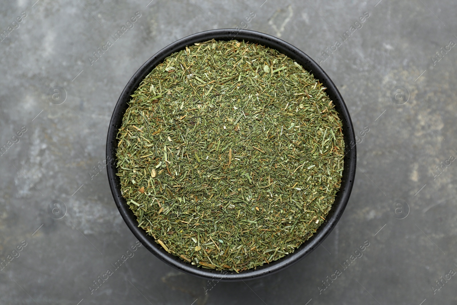Photo of Bowl with dried dill on grey table, top view