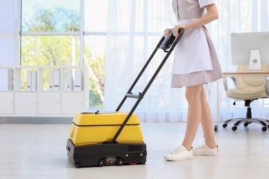 Photo of Female worker with floor cleaning machine indoors