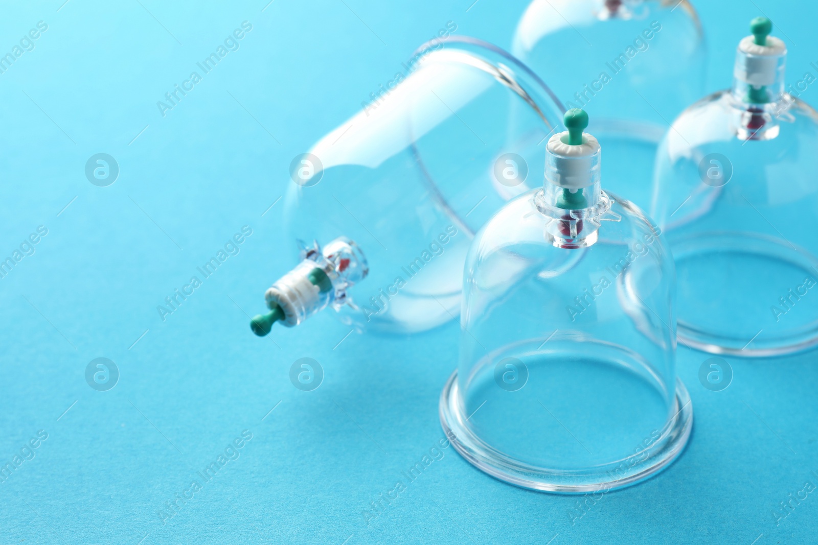 Photo of Plastic cups on light blue background, closeup with space for text. Cupping therapy