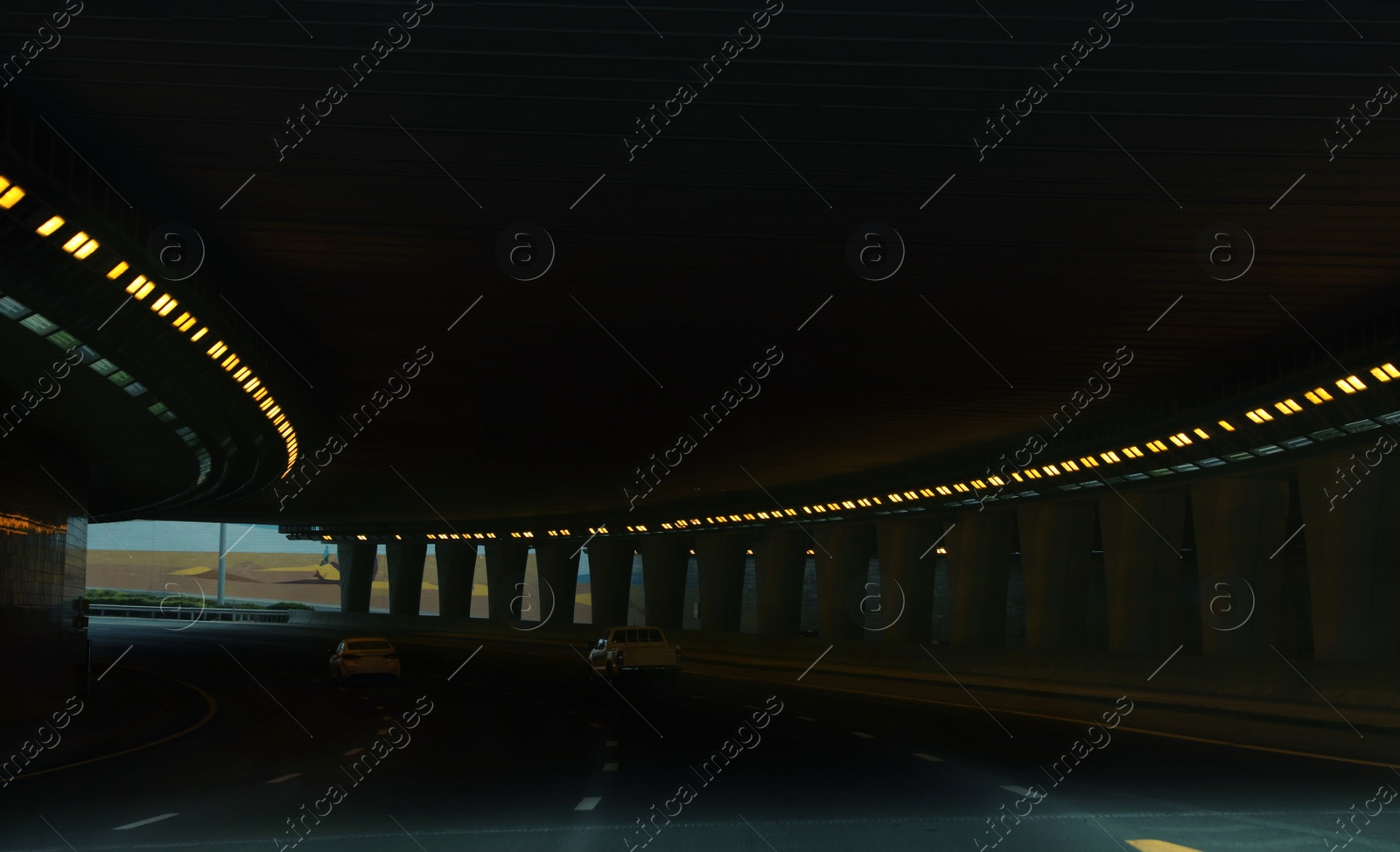 Photo of Modern cars driving through illuminated highway tunnel