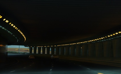 Photo of Modern cars driving through illuminated highway tunnel