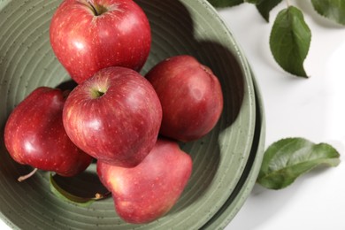 Fresh red apples and leaves on white table, flat lay