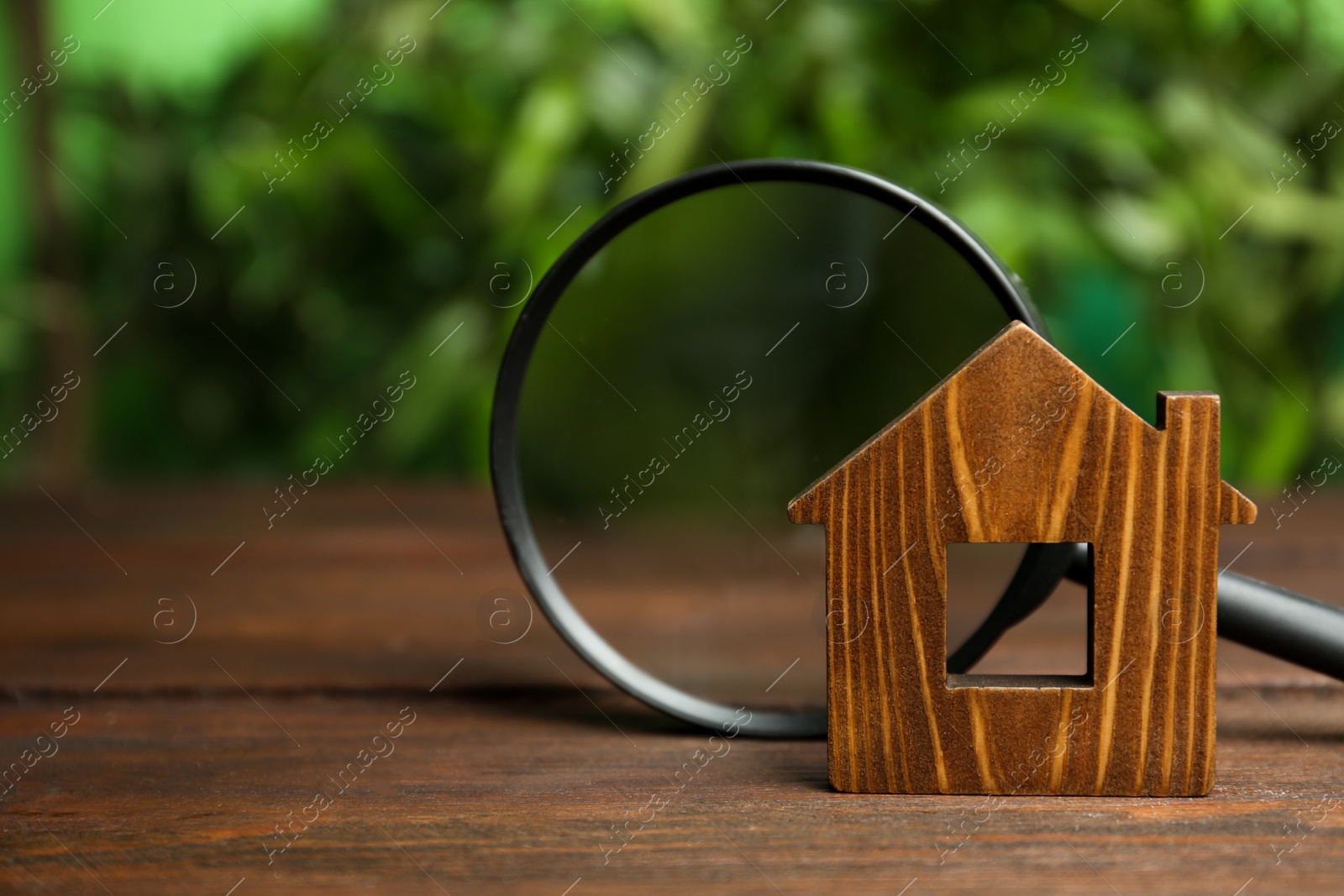 Photo of House model and magnifying glass on wooden table. Search concept