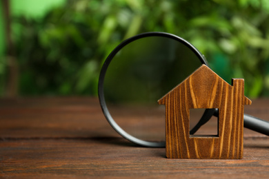 Photo of House model and magnifying glass on wooden table. Search concept