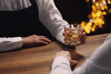 Photo of Bartender giving glass of whiskey to customer at bar counter, closeup