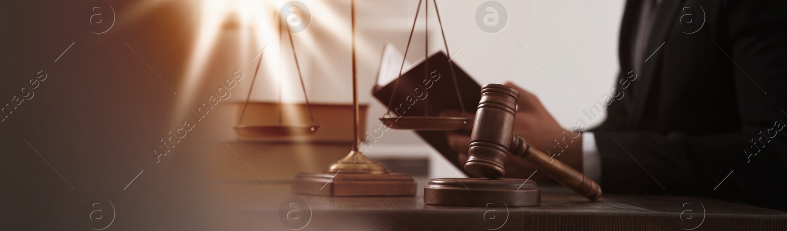 Image of Law and justice. Judge working at wooden table, focus on gavel. Banner design with space for text