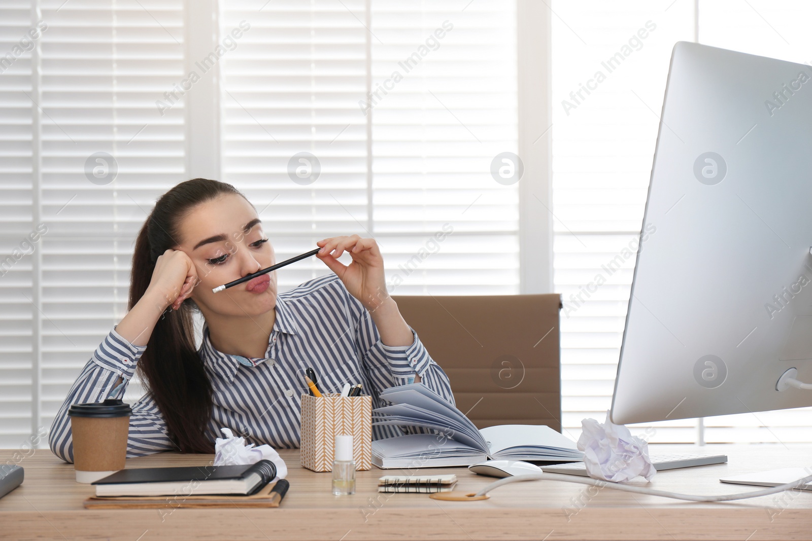 Photo of Lazy employee playing with pencil at table in office