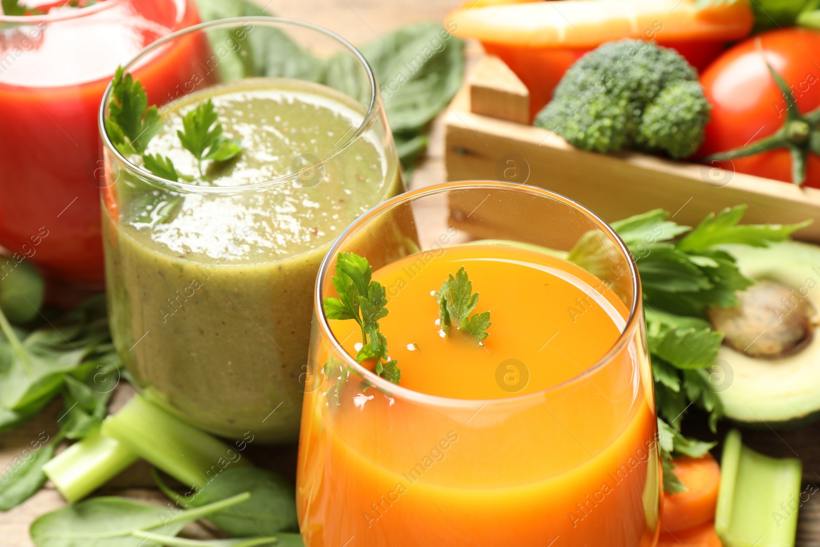 Photo of Delicious vegetable juices and fresh ingredients on wooden table, closeup