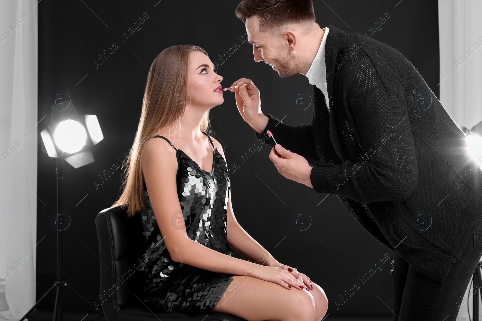 Photo of Professional makeup artist working with beautiful young woman in photo studio