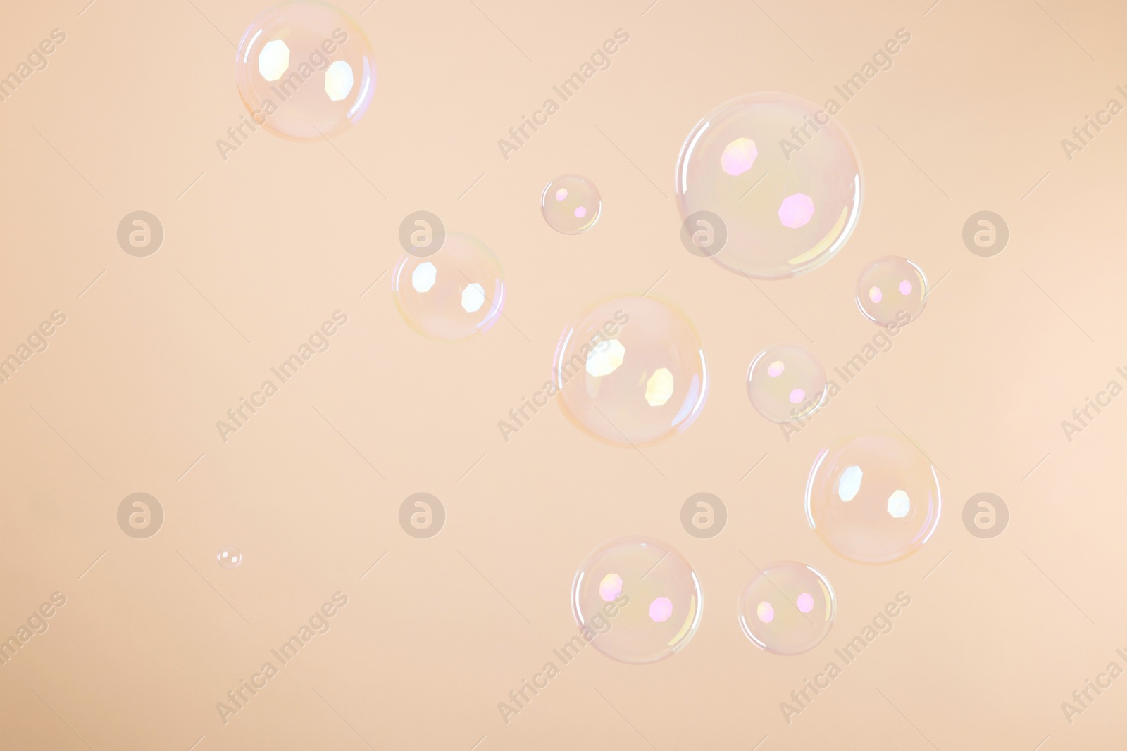 Photo of Many beautiful soap bubbles on beige background