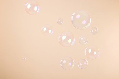 Photo of Many beautiful soap bubbles on beige background
