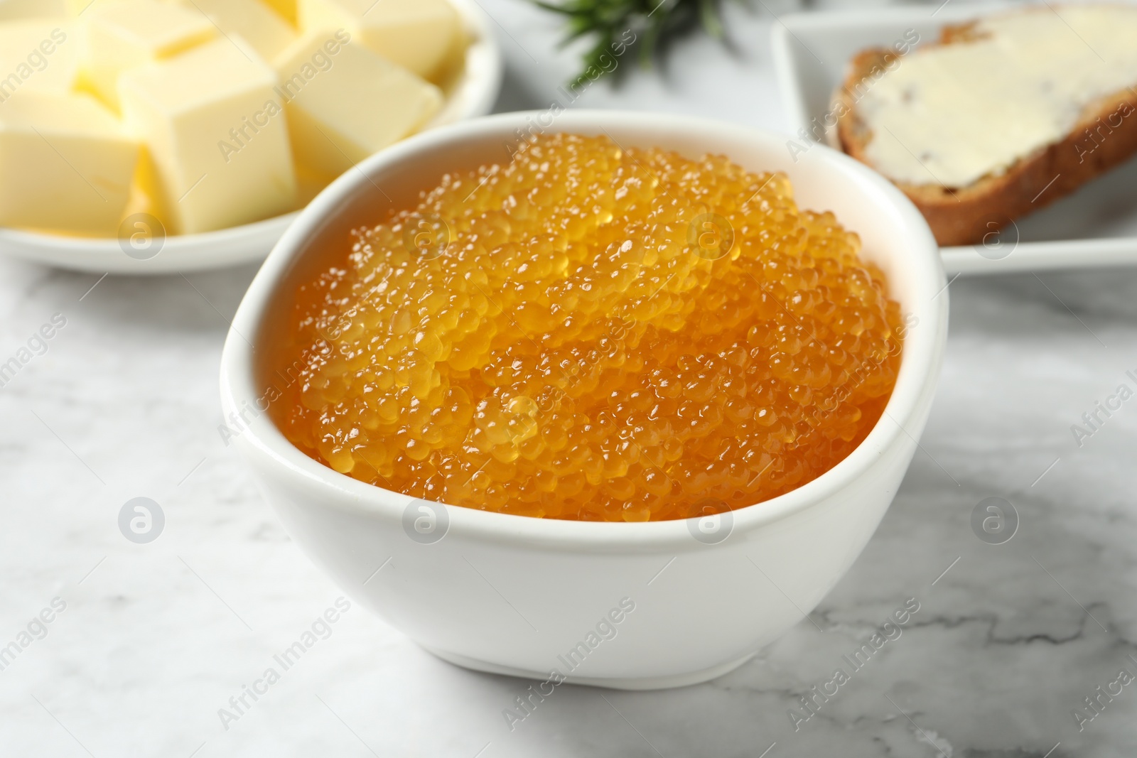 Photo of Fresh pike caviar in bowl on white marble table, closeup