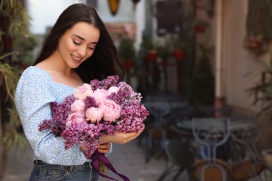 Beautiful woman with bouquet of spring flowers outdoors, space for text