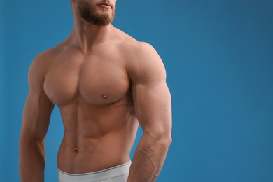 Photo of Muscular man showing abs on light blue background, closeup and space for text. Sexy body