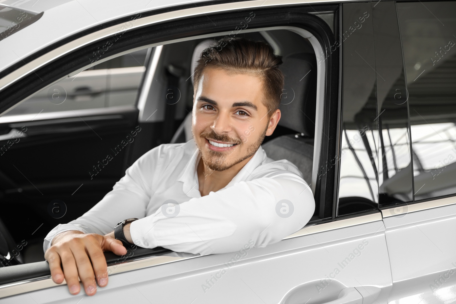 Photo of Young man testing new car in salon