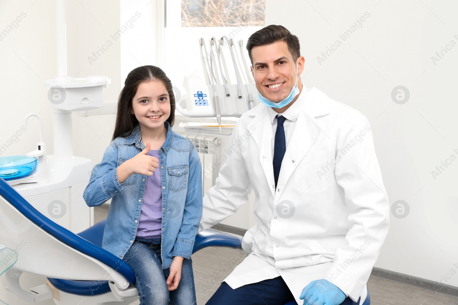 Photo of Professional dentist and little girl in clinic