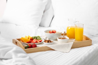 Photo of Wooden tray with tasty breakfast on bed