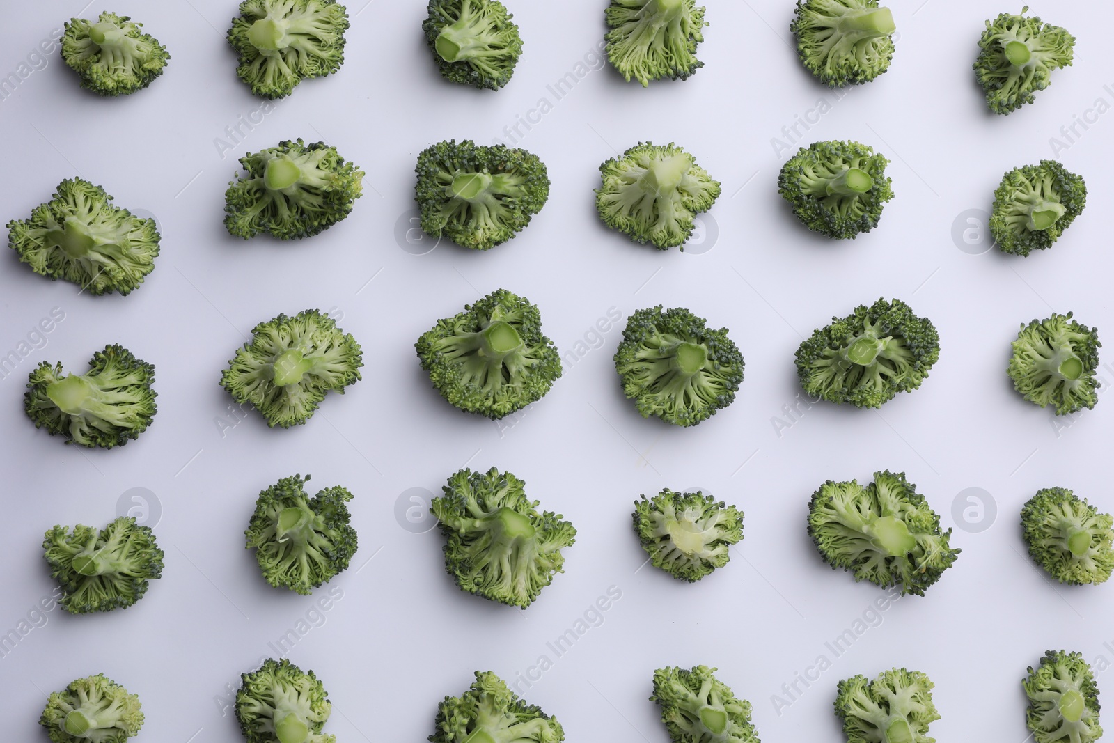 Photo of Many fresh green broccoli pieces on white background, flat lay