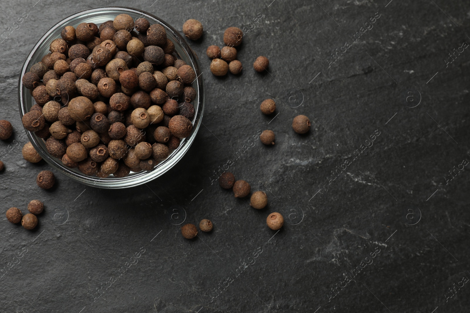 Photo of Dry allspice berries (Jamaica pepper) on black table, top view. Space for text