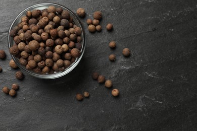 Photo of Dry allspice berries (Jamaica pepper) on black table, top view. Space for text