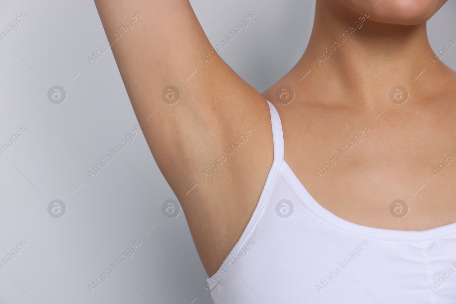 Photo of Young woman showing smooth skin after epilation on white background, closeup