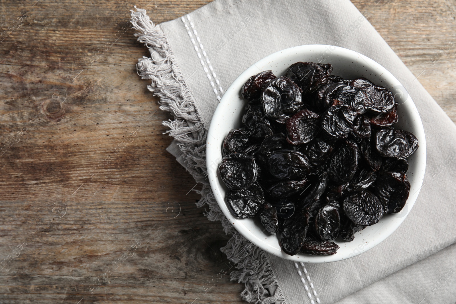 Photo of Bowl of sweet dried plums on table, top view with space for text. Healthy fruit