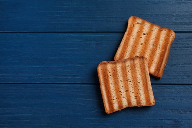 Photo of Slices of delicious toasted bread on blue wooden table, top view. Space for text