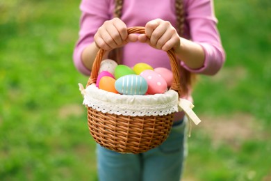 Photo of Easter celebration. Little girl holding basket with painted eggs outdoors, closeup