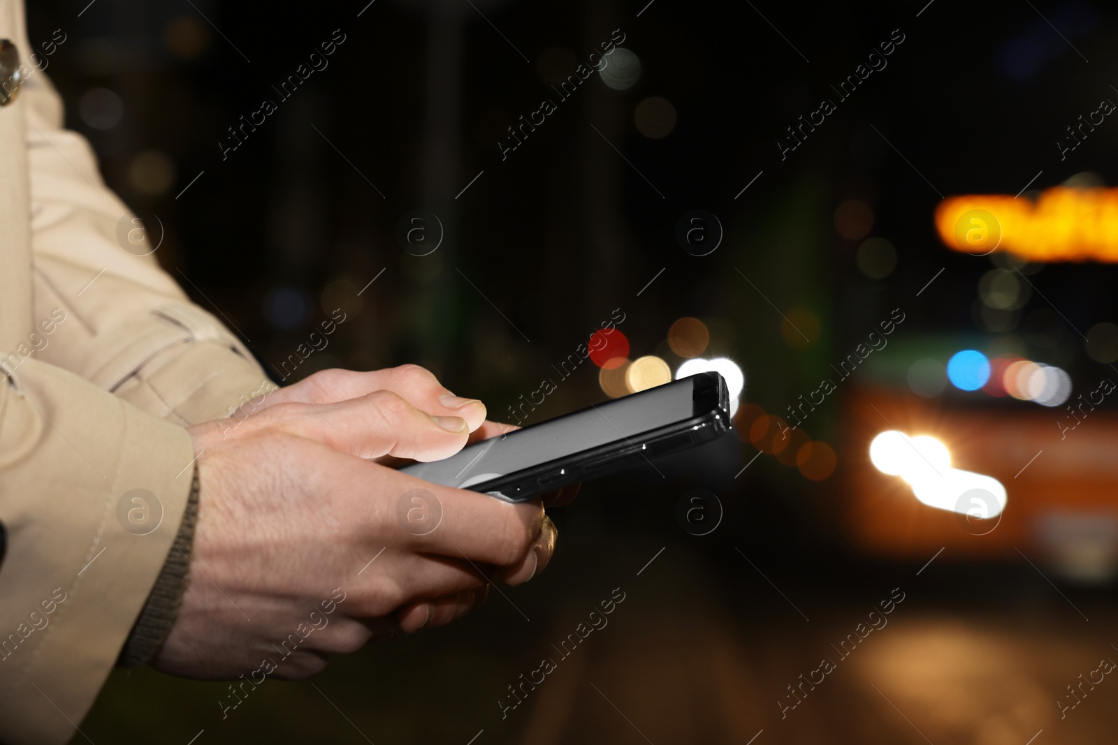 Photo of Man using smartphone on night city street, closeup